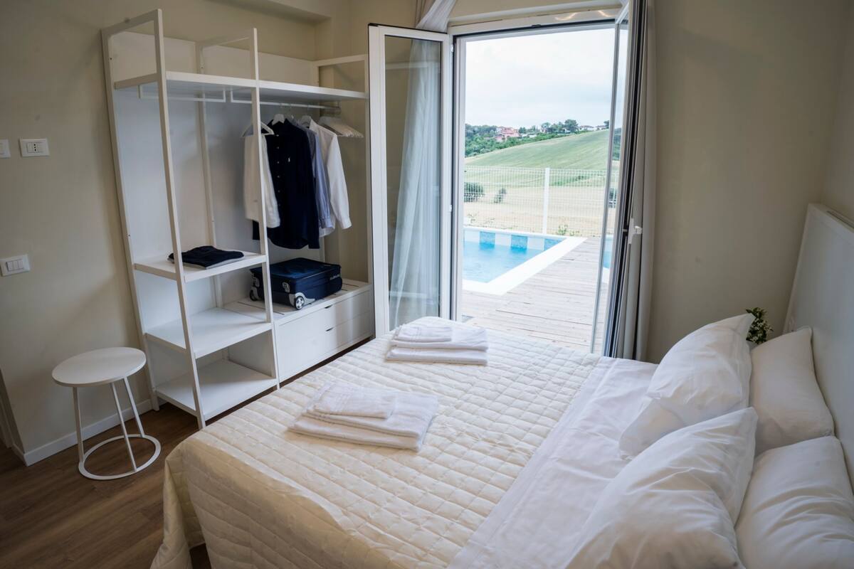 Une chambre avec un lit, une armoire, une petite table et une vue sur une piscine.