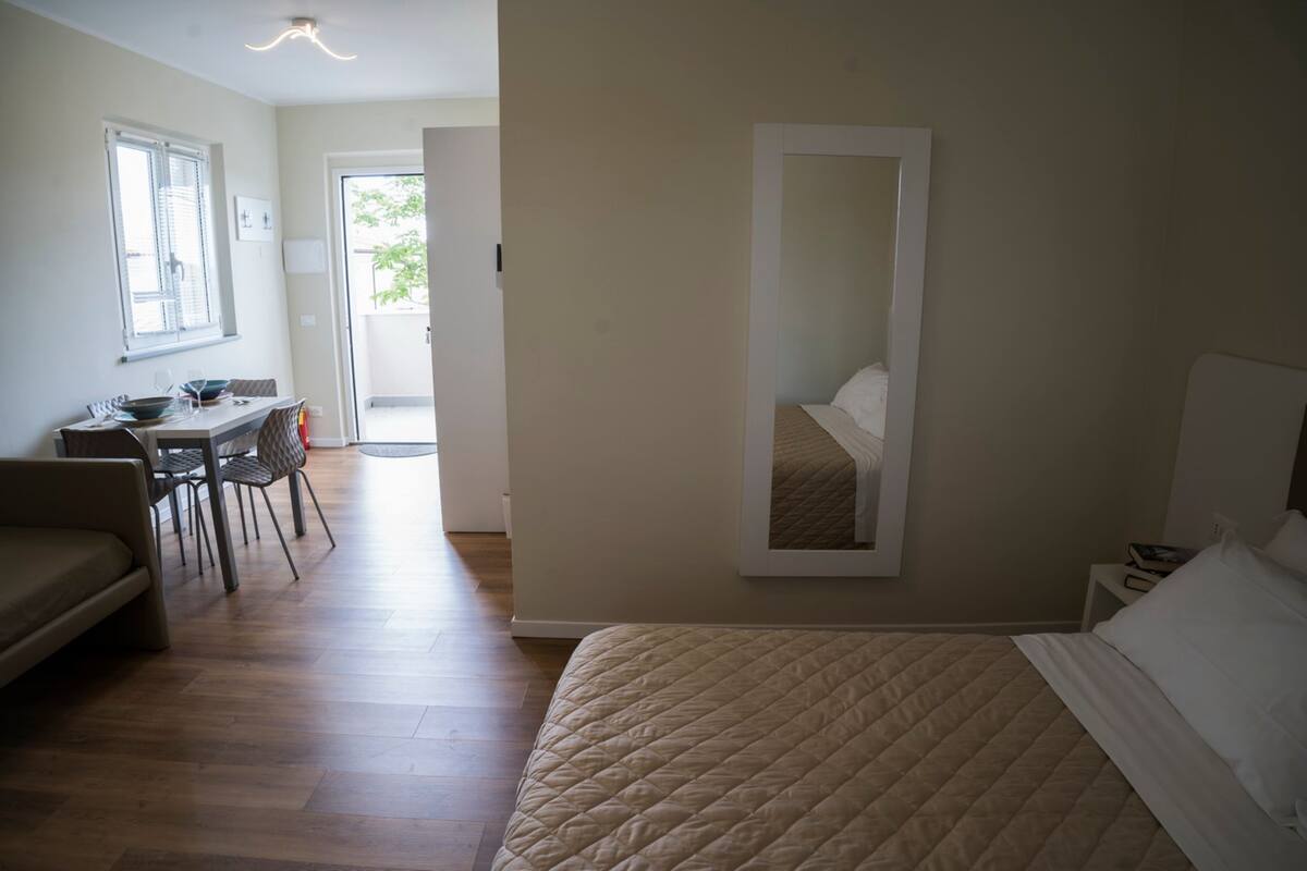 Une chambre à coucher comprenant un lit, une table de chevet, une chaise, un bureau et une fenêtre.