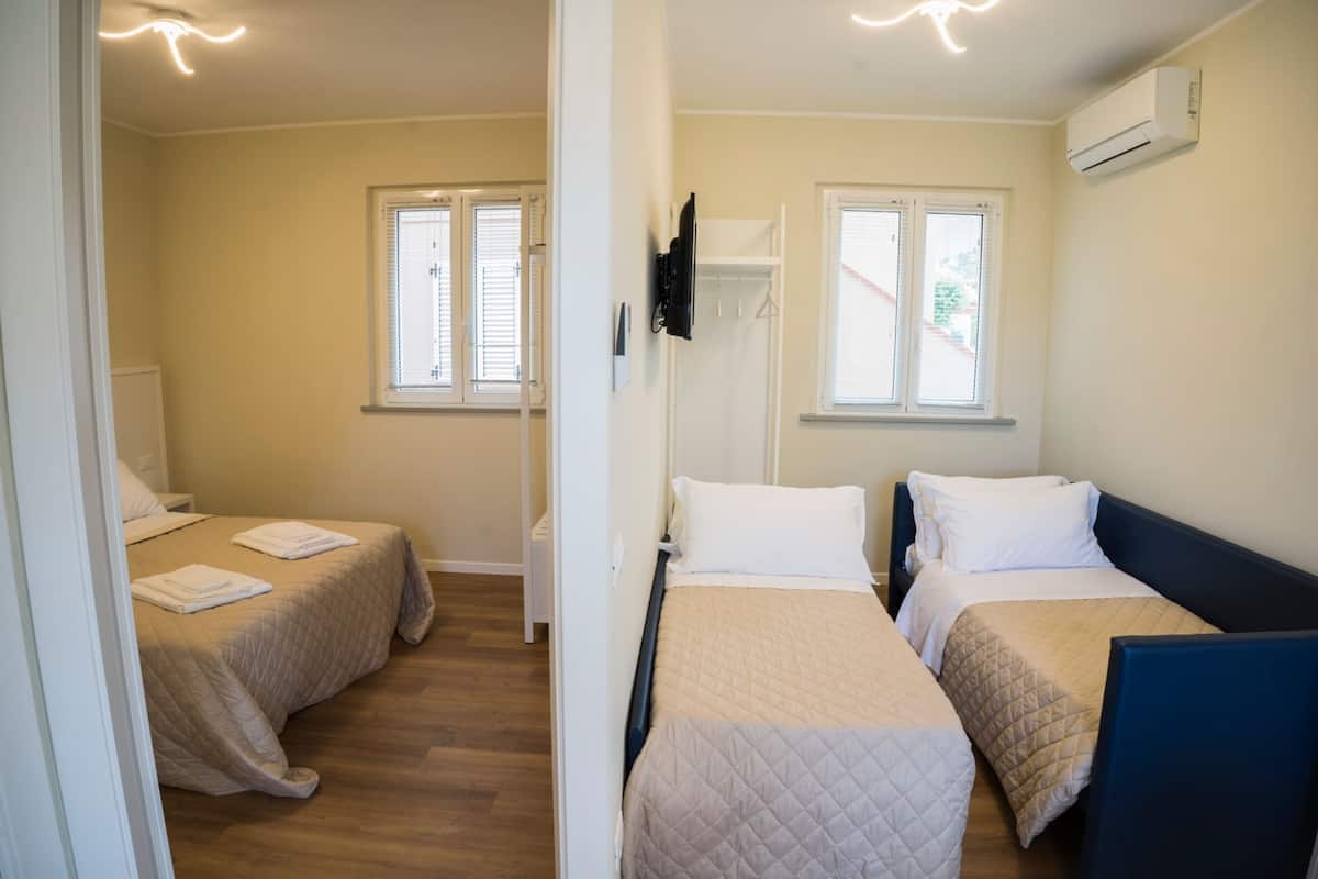 Une chambre avec deux lits, un téléviseur fixé au mur et un appareil de climatisation.