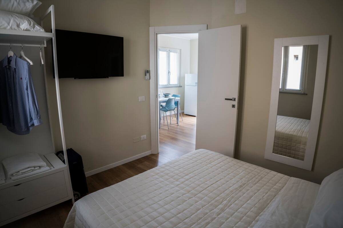 Une chambre comprenant un lit, une armoire, un téléviseur à écran plat, une porte donnant sur un coin repas et une fenêtre.