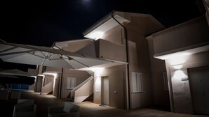 Un edificio de varios niveles, con zona de estar al aire libre y sombrillas, y un mostrador de recepción.