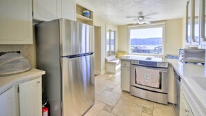 A kitchen with a stainless steel refrigerator, oven, and dishwasher, with a window offering a view of the outdoors. - Direct Beach Access: Getaway on Port Orchard! (Bremerton)