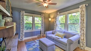 A living room with a grey sofa, an ottoman, a ceiling fan, and a window with curtains. - Direct Beach Access: Getaway on Port Orchard! (Bremerton)