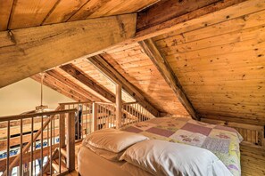 Een houten slaapkamer op zolder met een bed, kussens en een houten trap.