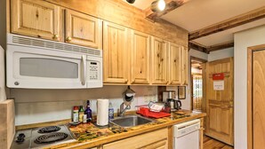 Une cuisine avec des meubles de rangement en bois, un four à micro-ondes blanc, une cuisinière et un évier.
