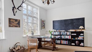 Une pièce avec une grande fenêtre, une bibliothèque, un bureau et une chaise.