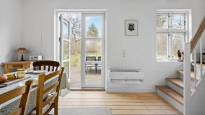 Une cuisine lumineuse et spacieuse, avec un plan ouvert, un sol en bois, un coin repas comprenant une table et des chaises, et un escalier.