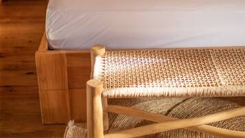 Un lit en bois avec une literie blanche, des coussins colorés et une serviette enroulée.