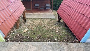 Eine kleine Holzhütte mit rotem Dach und zwei Stühlen auf der Veranda.
