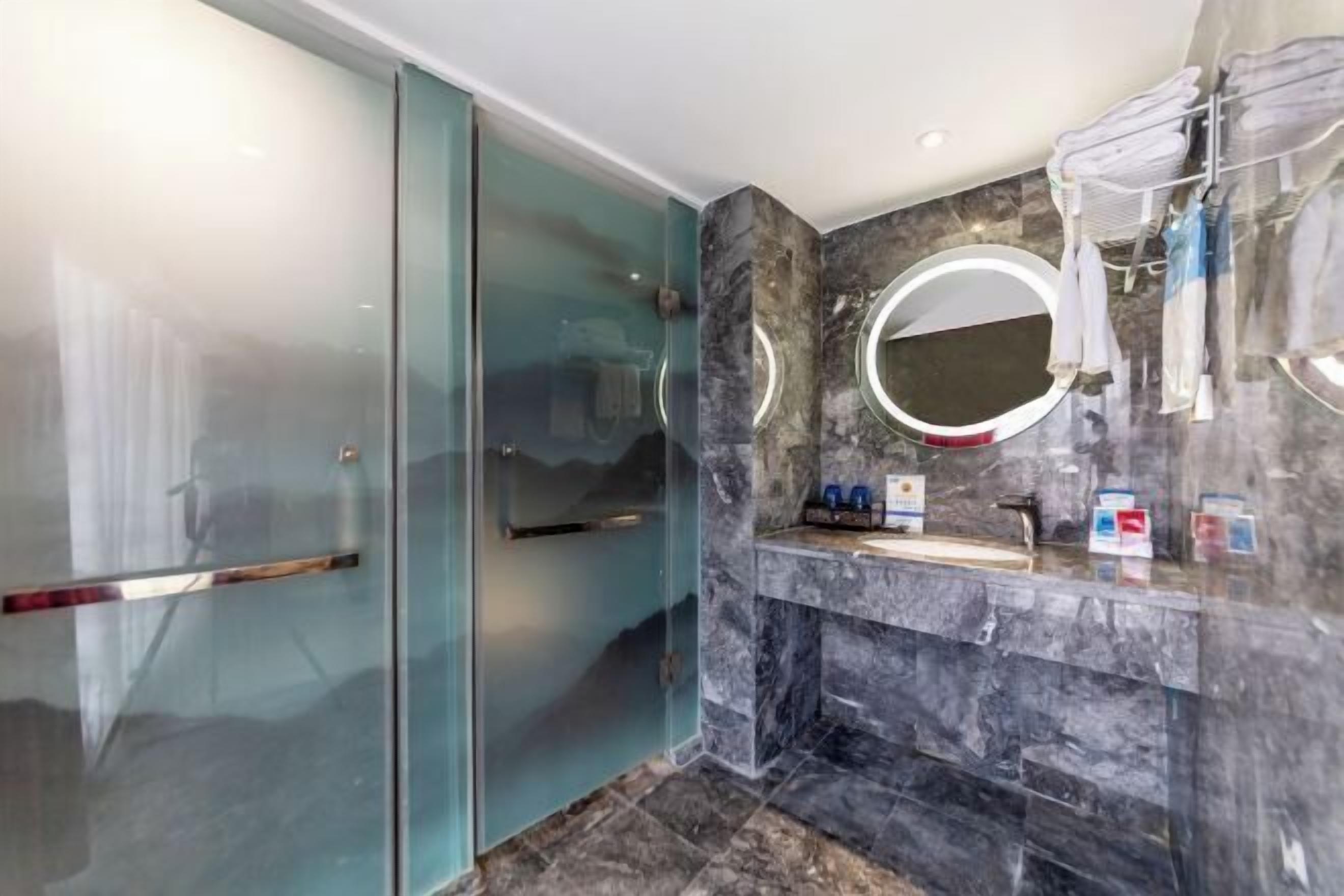 A modern bathroom with a glass shower enclosure, a marble sink, and a towel rack.