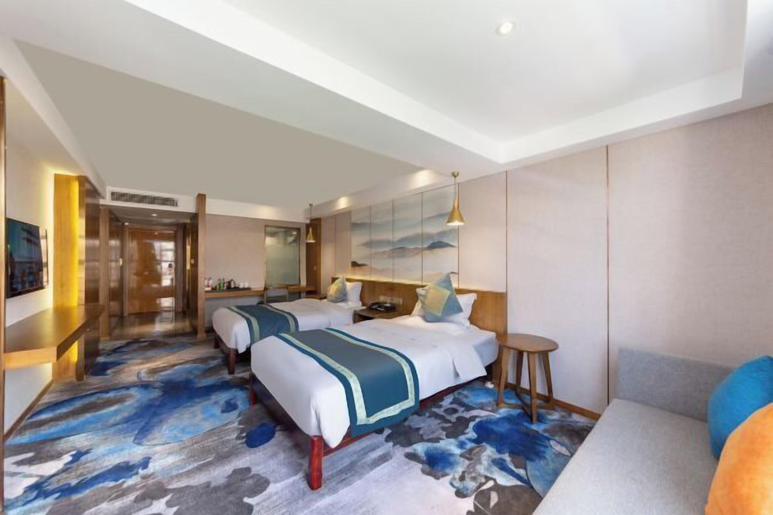 A hotel room with two beds, a sofa, a small round table, and a large mirror.