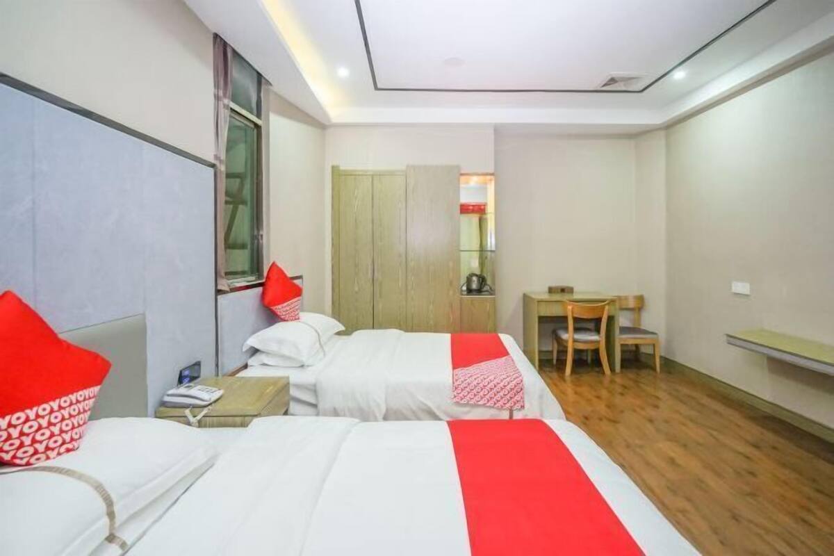 Une chambre d’hôtel avec deux lits, un bureau et une armoire.