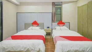 Ein Hotelzimmer mit zwei Einzelbetten, einem Nachttisch mit Telefon und einem Kleiderschrank.
