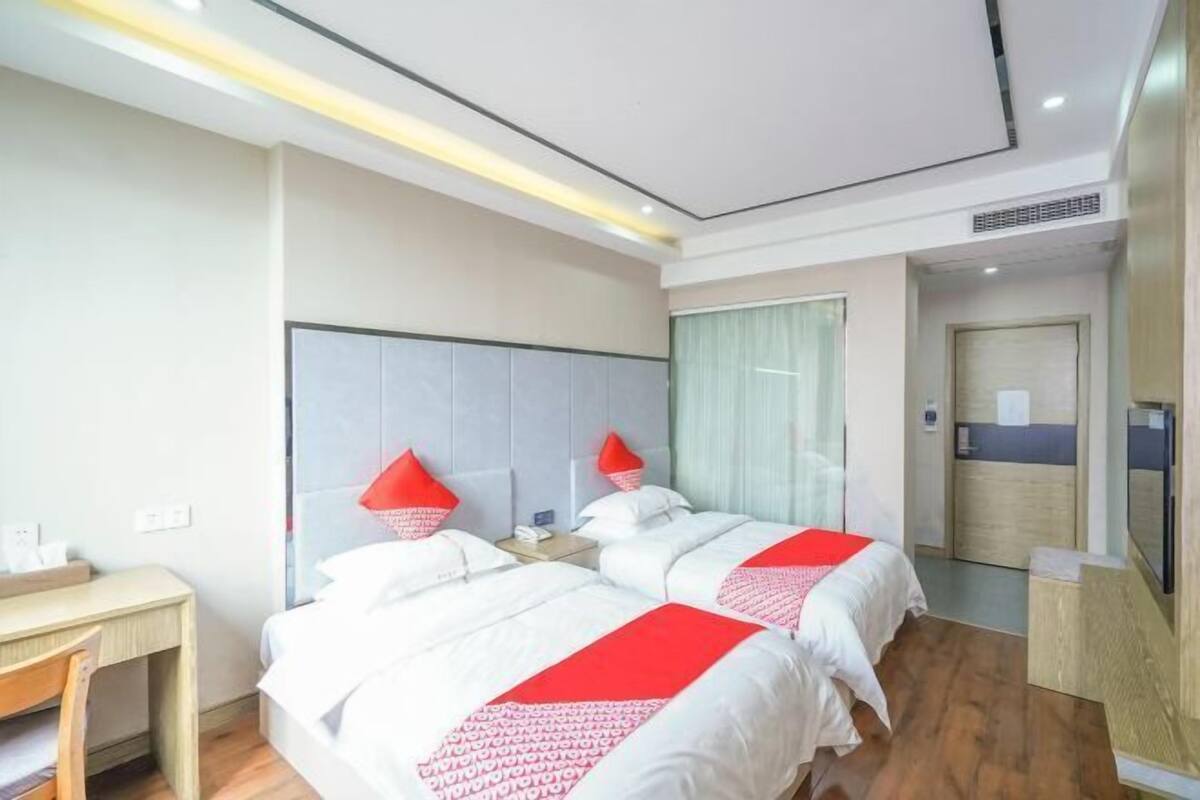 Une chambre d’hôtel avec deux lits, un bureau et un miroir.