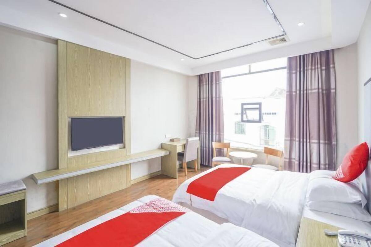 Une chambre d’hôtel avec deux lits, un téléviseur fixé au mur, un bureau et une chaise.