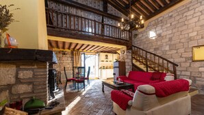 Una sala de estar acogedora con chimenea, un sofá y un comedor con sillas.