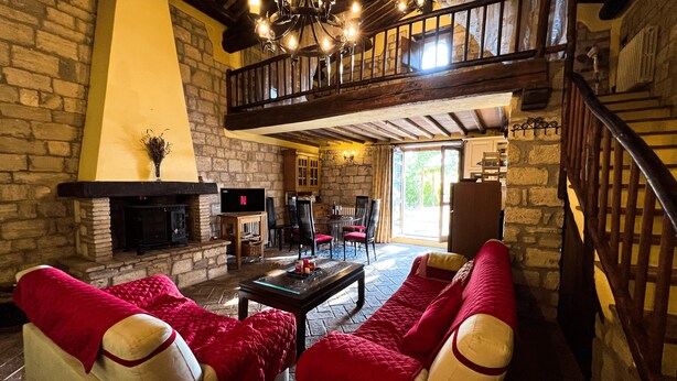 Una sala de estar acogedora con chimenea, un comedor y una escalera que sube a un nivel superior.
