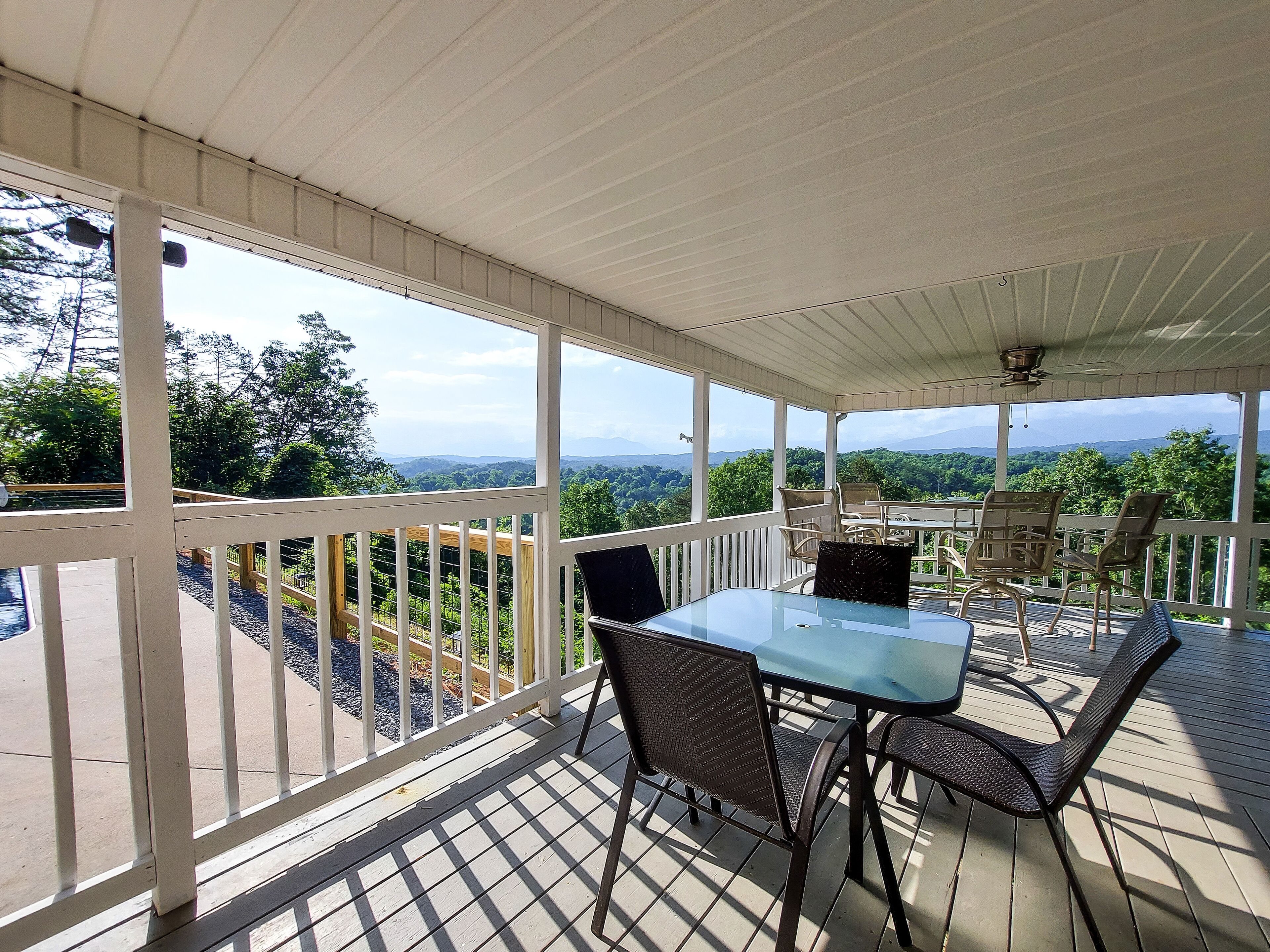 A covered patio with a table and chairs, overlooking a scenic landscape.