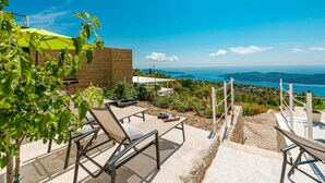 Un patio con sillones de descanso, una pared de madera y vista al mar.