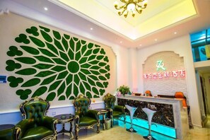 Un área de recepción con diseño moderno, que incluye una gran decoración de pared, un mostrador de recepción y un espacio de asientos.