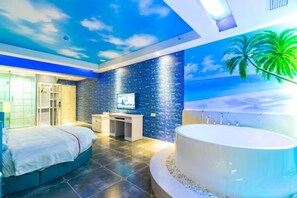 Un dormitorio con cama, escritorio, televisor y una bañera grande.