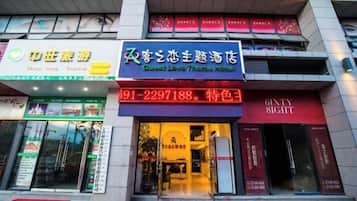 A hotel entrance with a prominent sign for 'Guest Love Theme Hotel' and a contact number.