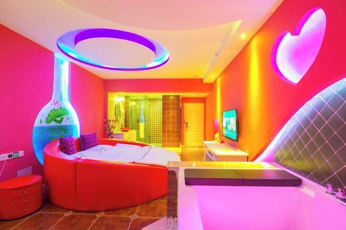 Una habitación vibrante con una cama curvada, un jarrón decorativo grande y un diseño mural con forma de corazón.