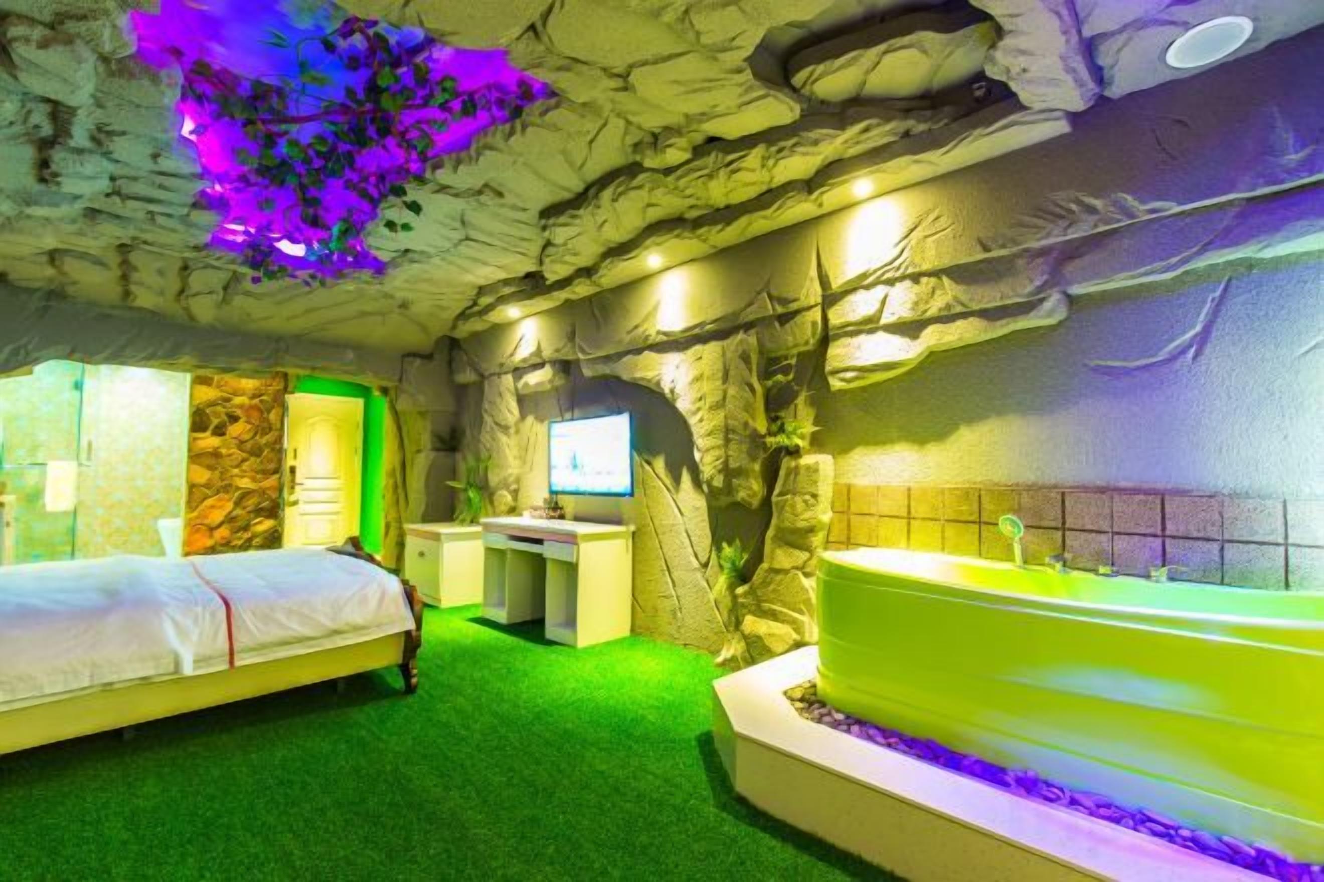 A room with a bed, a desk, a television, and a bathtub.