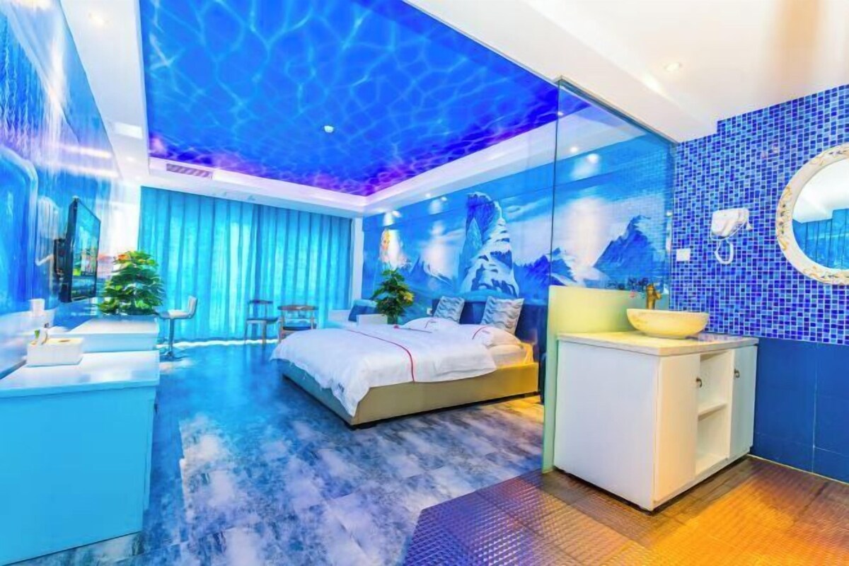 Une chambre à coucher moderne, avec un lit, une coiffeuse dotée d’un miroir, et une salle de bain comprenant un lavabo et des toilettes.