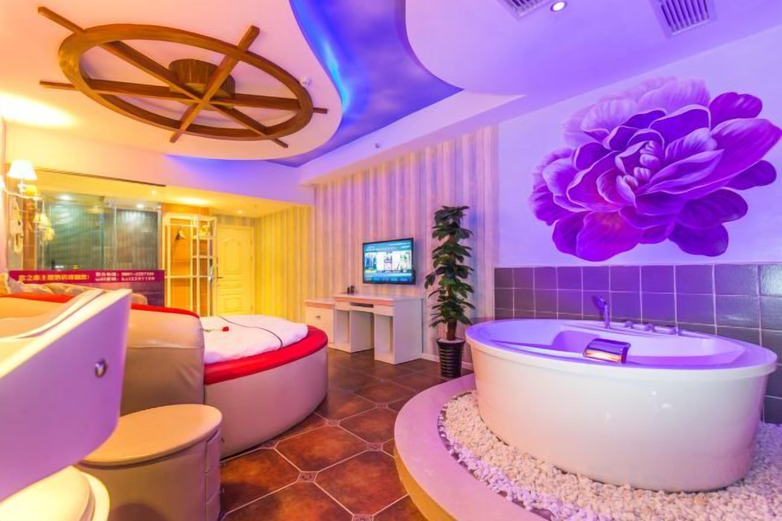 A modern hotel room with a large bathtub, a television, and a decorative wall.