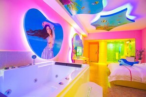 Une chambre dotée d’une grande baignoire, d’un lit et d’un mur orné d’un motif en forme de cœur.