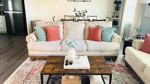 A living room with a beige sofa, a coffee table, and a patterned rug. - Adversity Home - Open Concept, with Pacman Machine. Close to I-40 Airport (Amarillo)