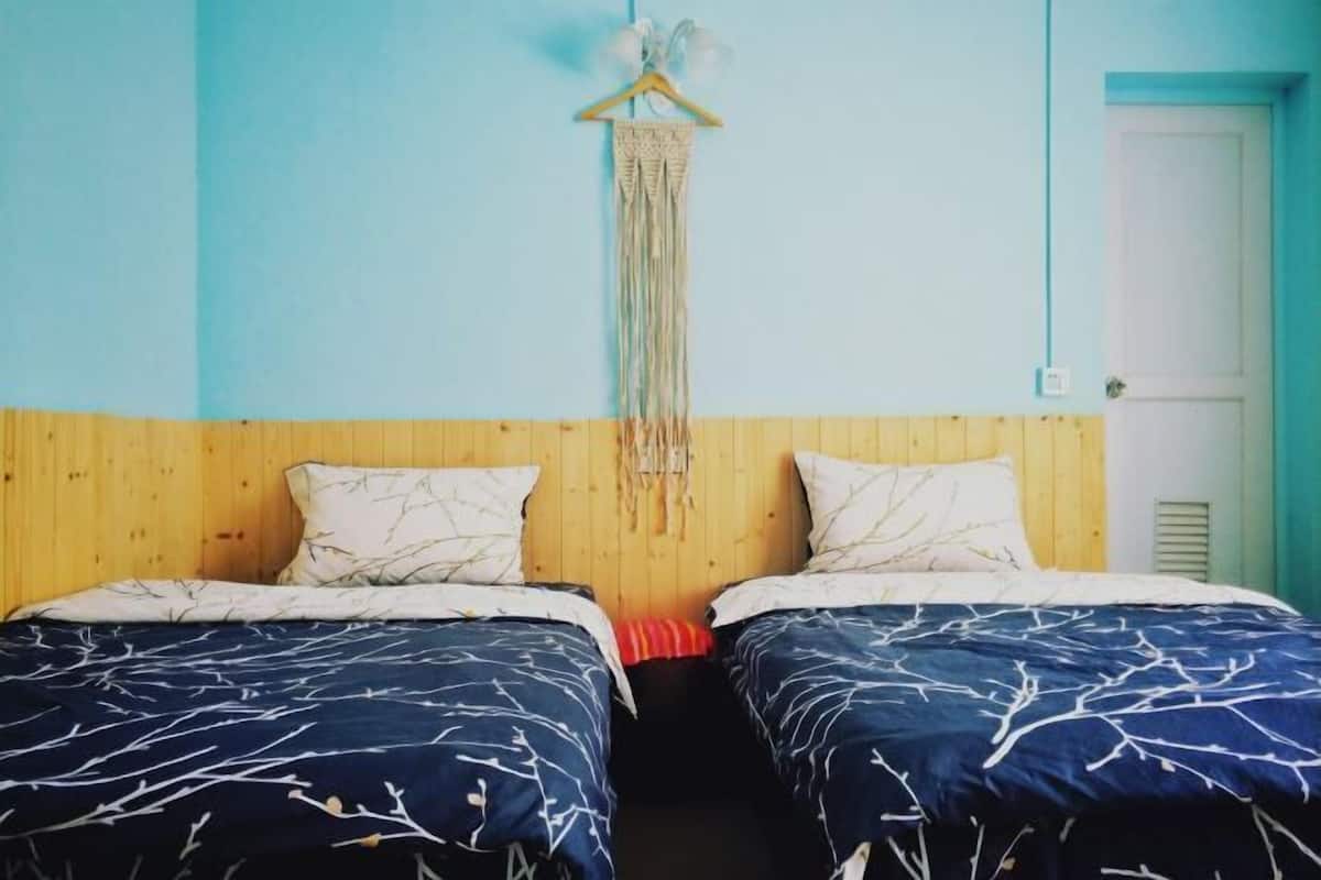 Een kamer met twee bedden, een houten hoofdbord en een wanddecoratie.