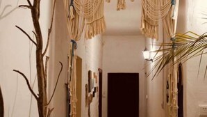 Un couloir décoré de macramés, avec une plante et une porte au fond.