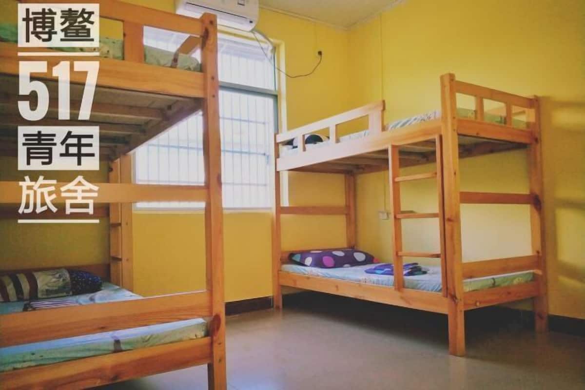 Een kamer met twee stapelbedden, houten wanden en een raam met zonwering.