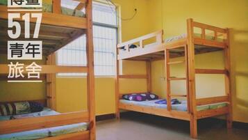 Een kamer met twee stapelbedden, houten wanden en een raam met zonwering.