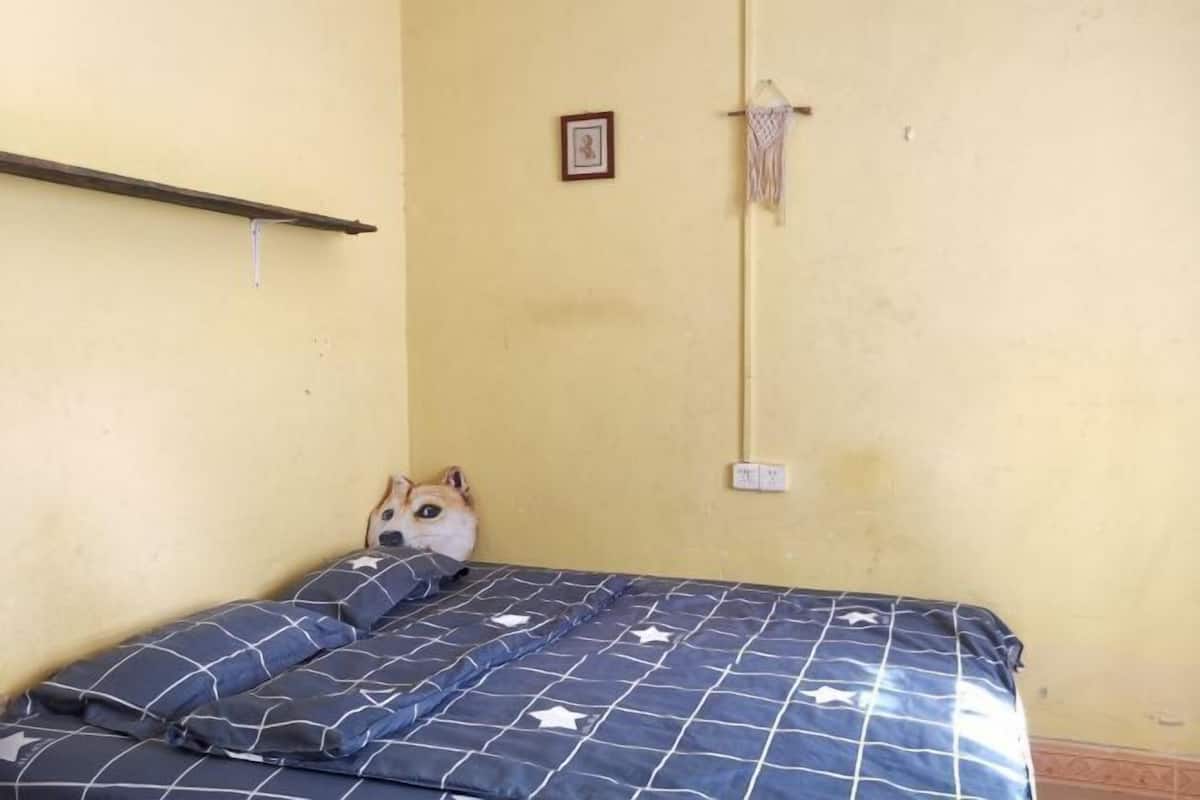 Een slaapkamer met een bed, kussens, een foto aan de muur en een handdoek.