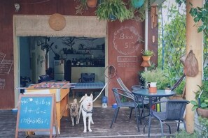 Un café al aire libre con una mesa de madera, sillas y un cartel.