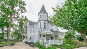 A two-story house with a prominent tower, a front porch, and a well-maintained garden.