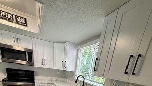 A modern kitchen with white cabinetry, stainless steel appliances, and a marble countertop.