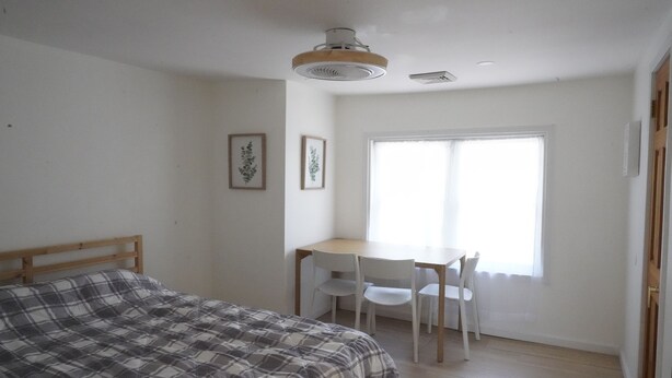 A bedroom with a bed, a desk, and chairs.