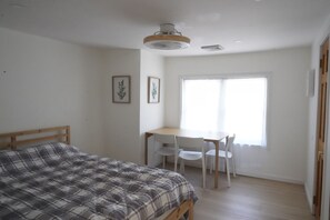 A bedroom with a bed, a desk, and chairs.