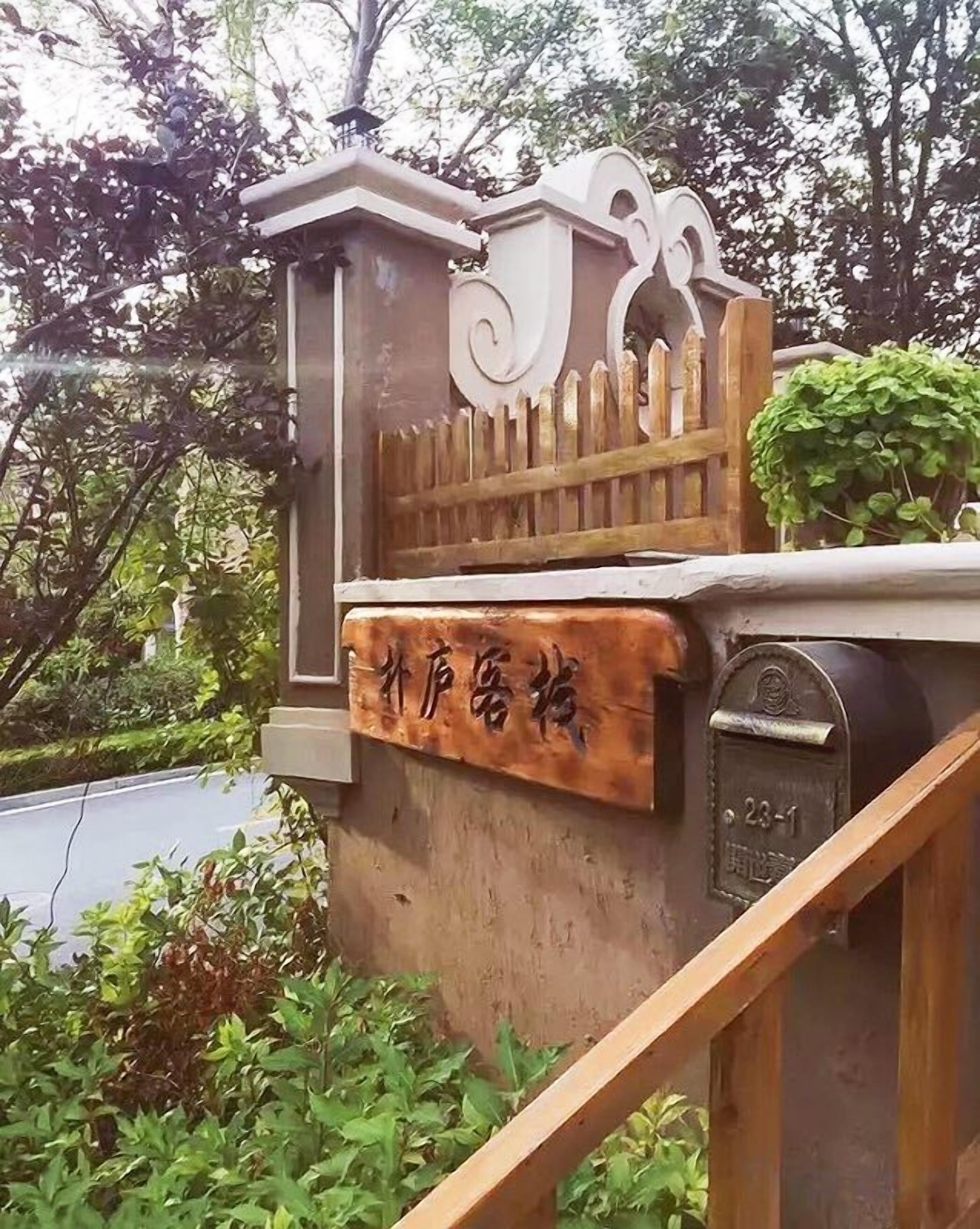 A wooden mailbox with a mailbox slot, a wooden fence, and a sign with Chinese characters.