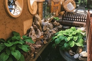 A garden with a stone wall, potted plants, and a wooden fence. - Pulu Inn (Dalian)