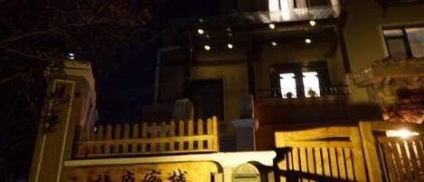 A building with a gated entrance, a sign with Chinese characters, and a balcony with lights.