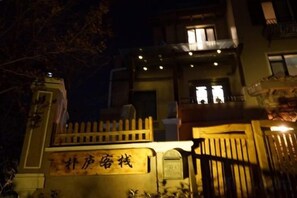 A building with a gated entrance, a sign with Chinese characters, and a balcony with lights. - Pulu Inn (Dalian)