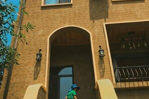 Un edificio con una entrada arqueada, una puerta negra y una ventana con una reja de metal.