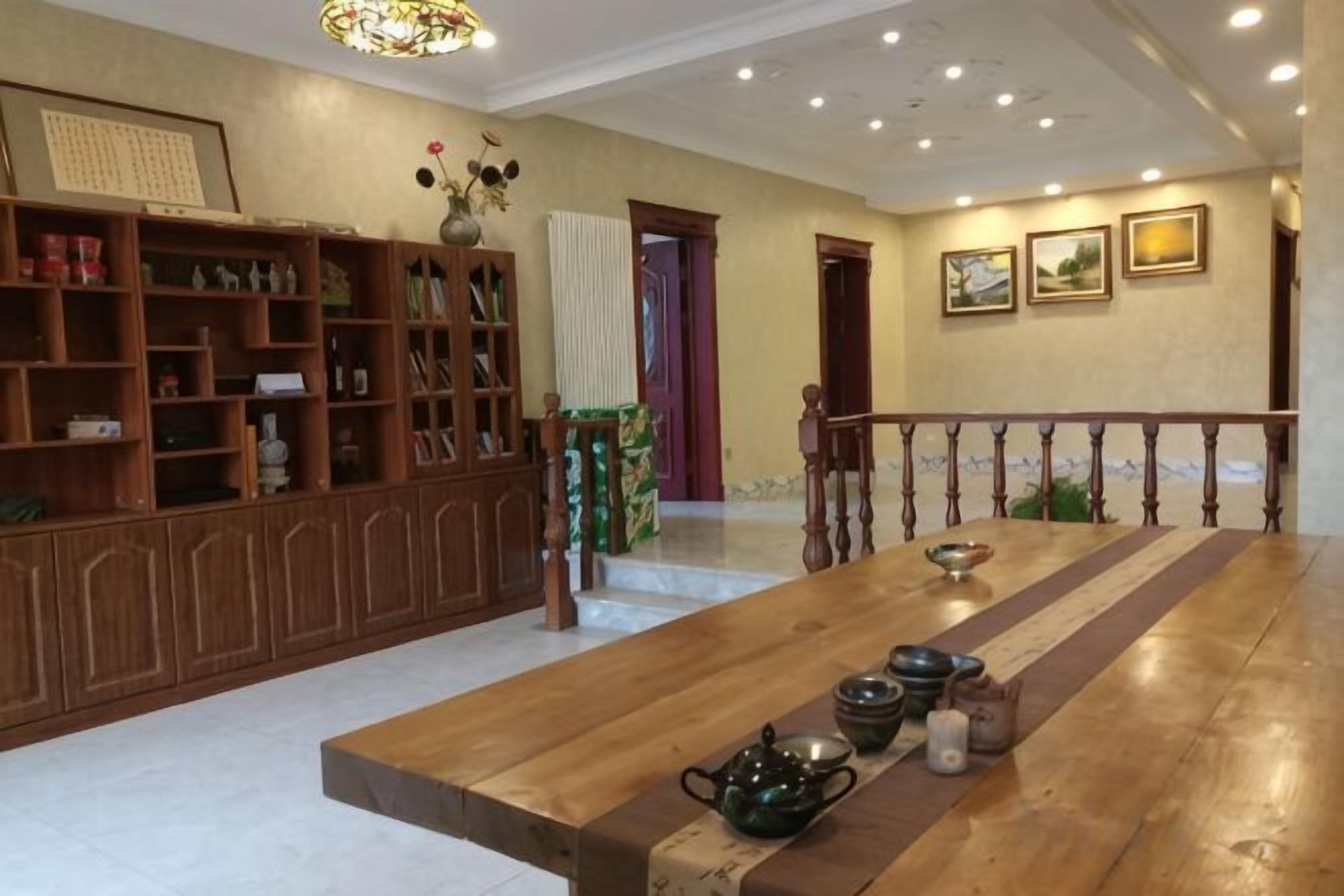 Una habitación amplia con una mesa de comedor de madera, una estantería y un jarrón decorativo.