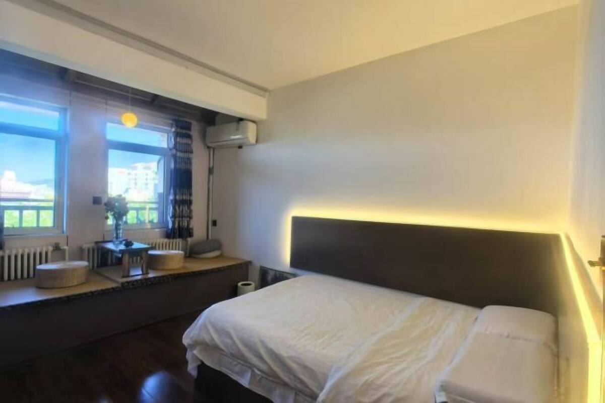 Una habitación de hotel moderna con una cama grande, una ventana con vistas, una mesita de noche y una lámpara.