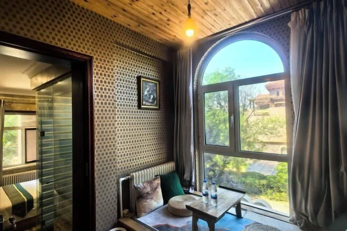 Una habitación acogedora con un ventanal grande, techo de madera y pared con diseño.